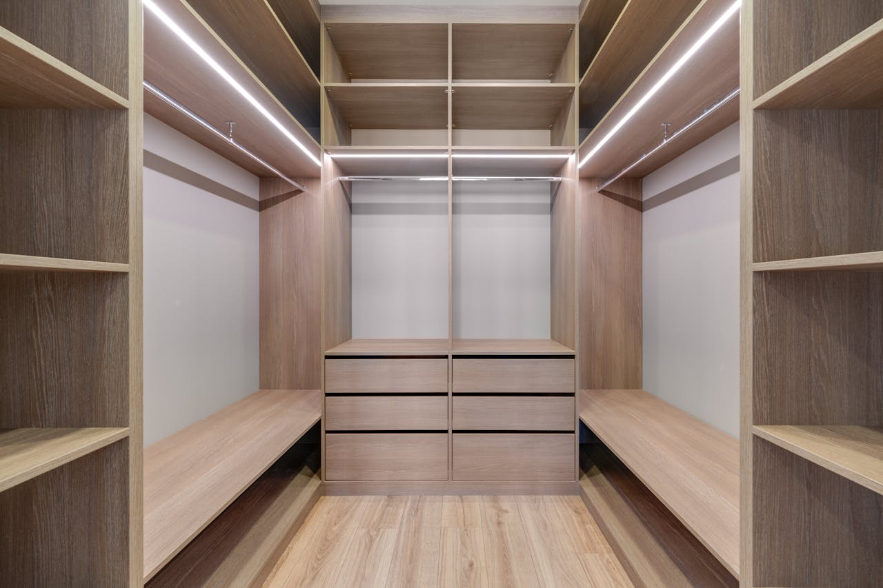 services-03 Spacious walk-in closet with wooden shelves and LED lighting creates a minimalist and modern design.