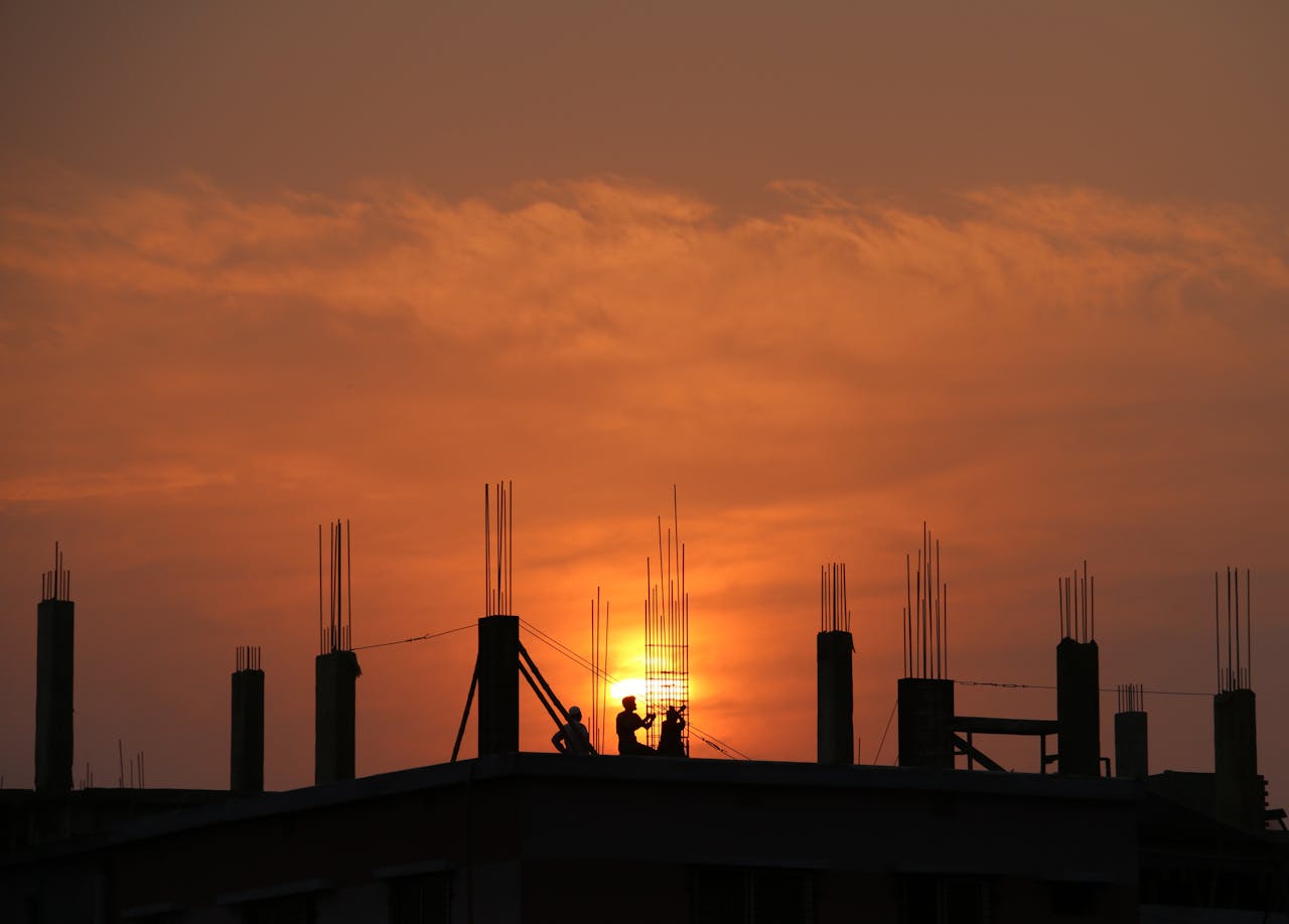 journey Silhouette of workers on a construction site against a vibrant sunset sky.